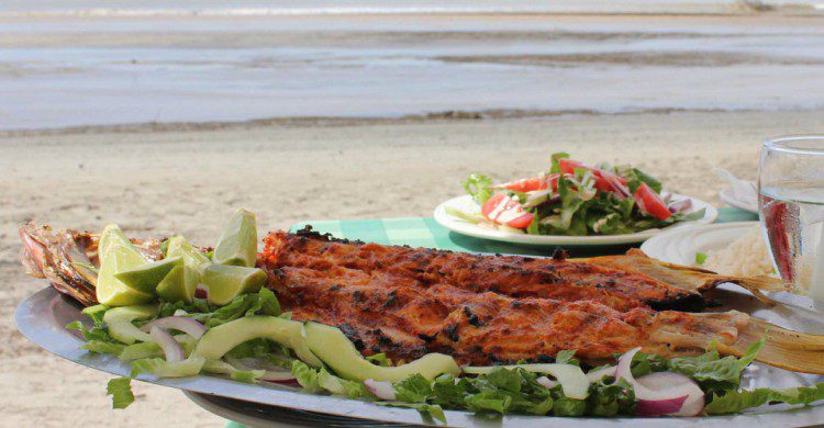 Pescado zarandero en la playa, con agua y ensalada