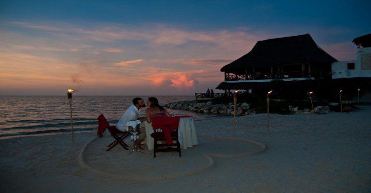 pareja cenando a la orilla del mar con corazón dibujado en la arena