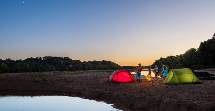 Jóvenes acampando a la orilla del mar al anochecer