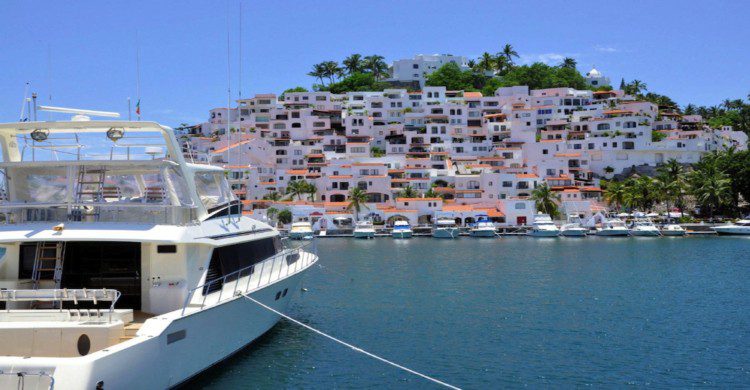 Playa de Manzanillo Colima de día con barco blanco en el mar azul