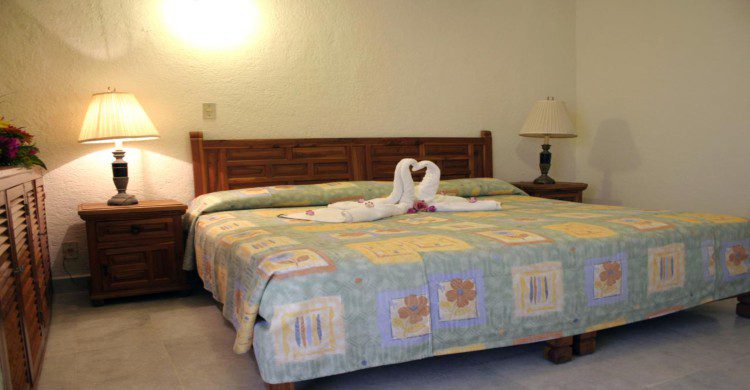 Habitación con lampara en cendida y cama matrimonial en el Hotel Suites Jazmin