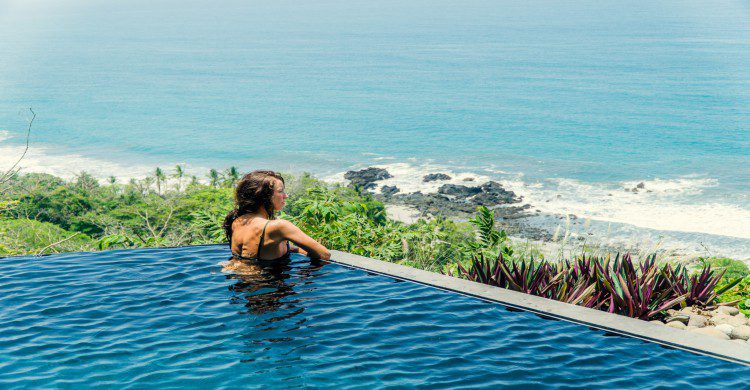 Mujer en una piscina viendo al mar en Montezuma, Costa Rica