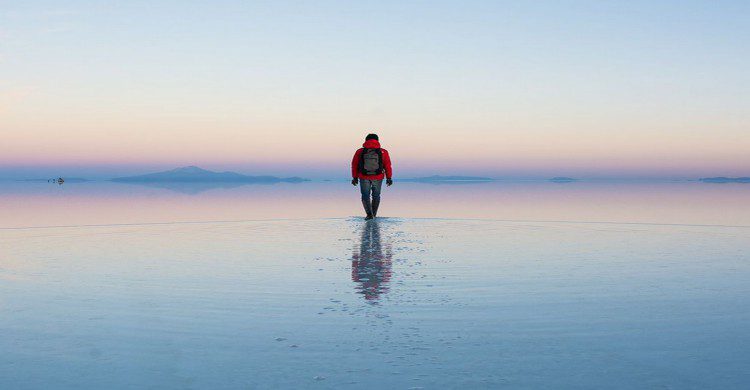 Hombre con mochila caminando en medio de El Salar, Bolivia