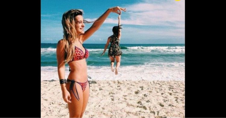 Mujer simulando que carga a otra en la playa de día