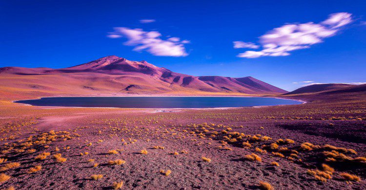 Cielo azul, lago y montañas en tonos rojizos purpura en el Desierto de Atacama, Chile