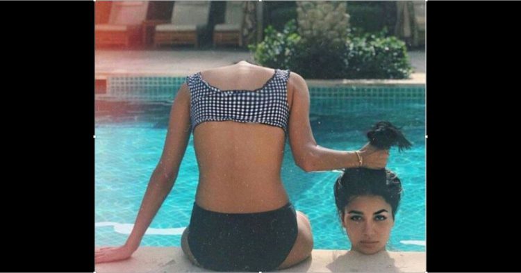 mujer sentada en una piscina simulando sostiene su cabeza arrancada