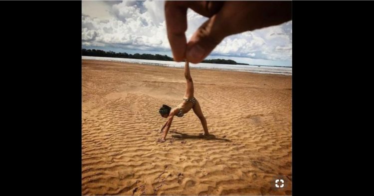 Mano simulando que sostiene a una mujer en la playa de día