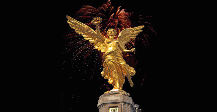 Ángel de la Independencia de noche con fuegos artificiales detrás 