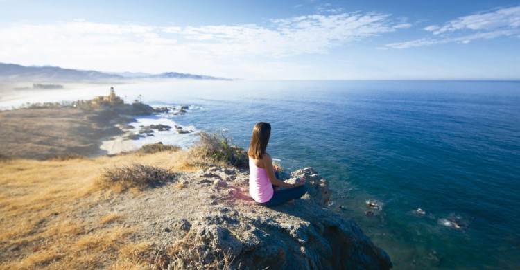 Mujer meditando sola en Playa de Todos Santos de día con mar azul