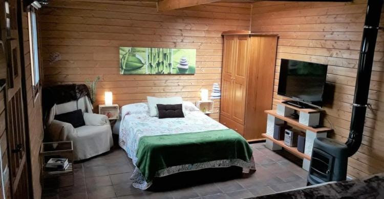 Recamara al interior de una cabaña de madera con televisión