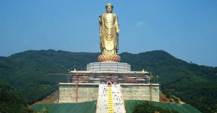 Estatua dorada con cielo azul y montañas de día