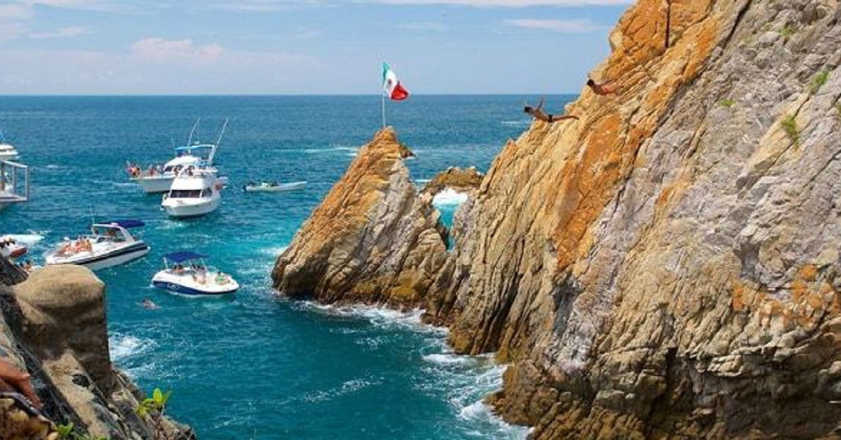 Hombres saltando de La Quebrada de Acapulco de día con cielo azul